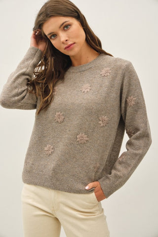 Woman wearing a brown floral sweater and white pants