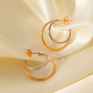 Gold and silver hoop earrings on a soft beige fabric background