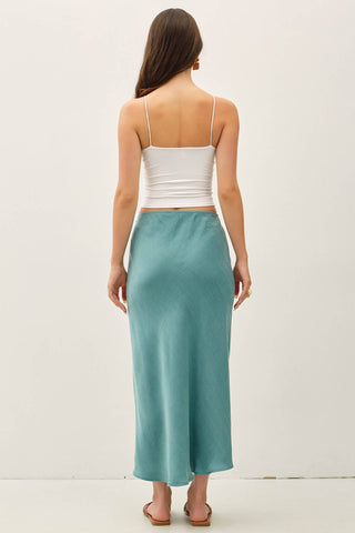 Woman wearing a white top and teal skirt on a white background