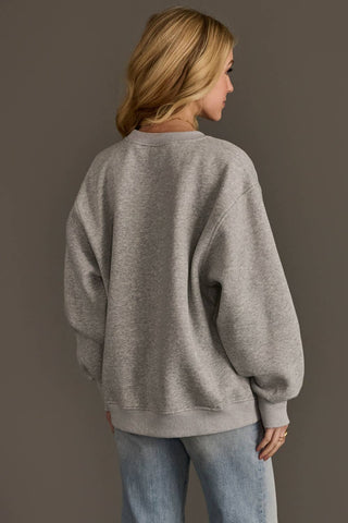 Person wearing a gray sweatshirt and light blue jeans against a plain background
