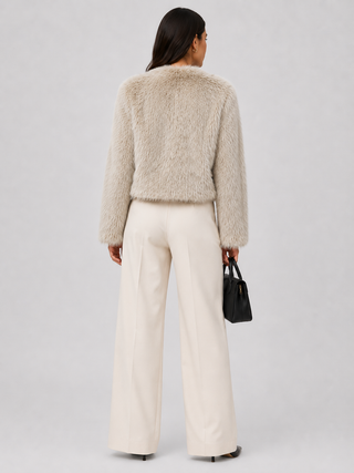 Back of a woman wearing a faux fur jacket and winter white slacks