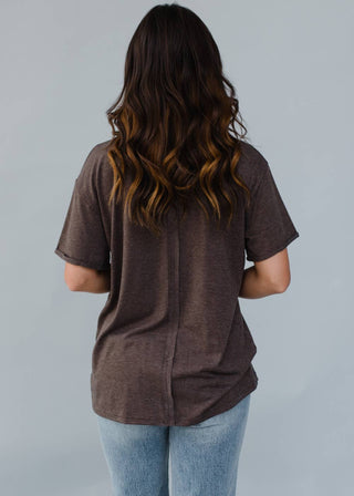 Person wearing a brown shirt and blue jeans against a gray background