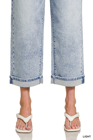 Light blue jeans worn by a person with white sandals on a white background