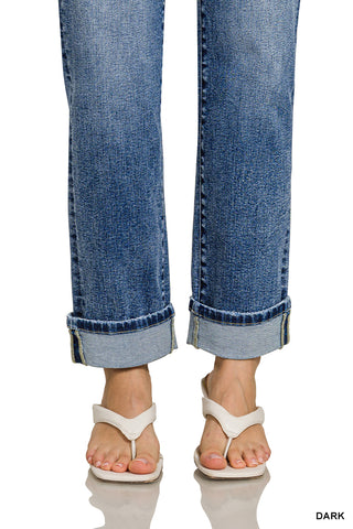 Close-up of rolled-up blue jeans and white sandals on a white background
