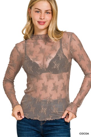 Woman wearing a sheer brown lace top with long sleeves on a white background