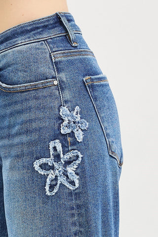 Blue jeans with floral embellishments on a white background
