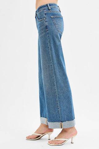 Cuffed blue jeans against a white background