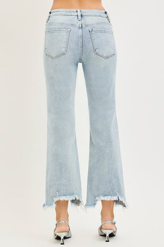 Light wash blue denim flare jeans with a raw frayed hem, shown from the back on a model wearing silver high-heeled sandals against a plain white background.