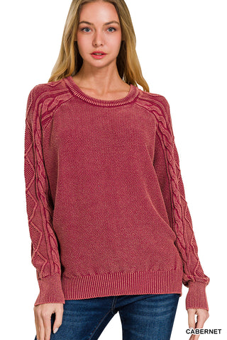 Woman wearing a cabernet sweater with cable knit details on a white background
