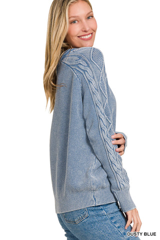 Woman wearing a dusty blue cable knit sweater on a white background