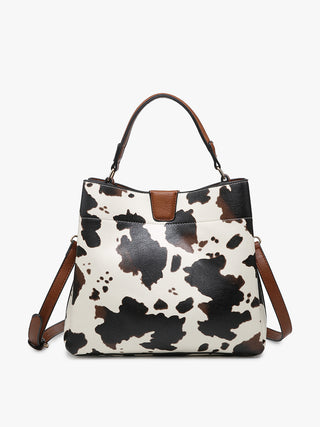 Cow print handbag with brown leather straps on a white background