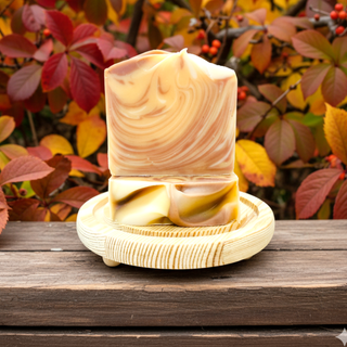 Decorative candle with wavy pattern on a wooden stand against an autumn leaf background