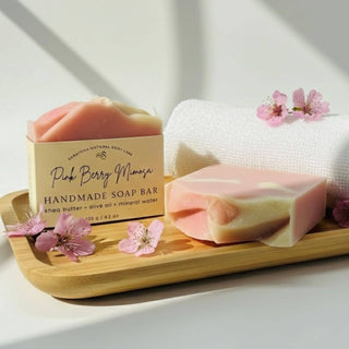 Handmade soap bar with packaging on a wooden tray with cherry blossoms