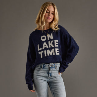 Woman wearing a navy sweater with 'ON LAKE TIME' text on a gray background