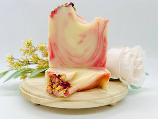 Marbled soap bar with floral elements on a wooden stand, surrounded by flowers on a light background