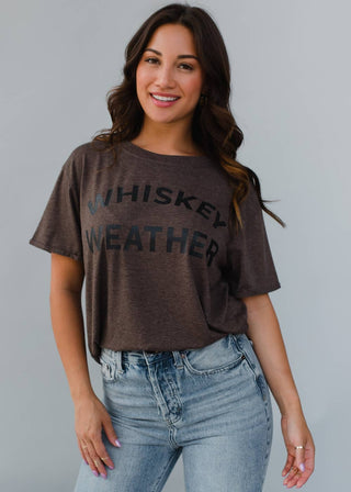 Woman wearing a brown t-shirt with 'WHISKEY WEATHER' text against a gray background