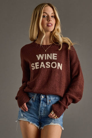 Woman wearing a maroon sweater with 'WINE SEASON' text against a gray background