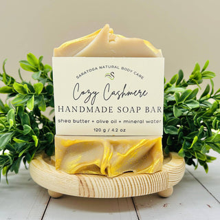 Handmade soap bar on a wooden stand with greenery in the background