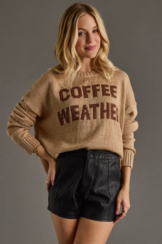 Woman wearing a beige sweater with 'COFFEE WEATHER' text on a gray background