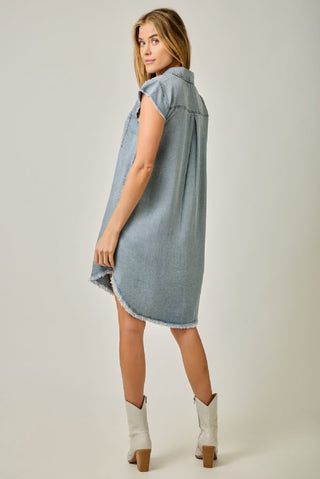 Woman wearing a light blue denim dress on a plain background