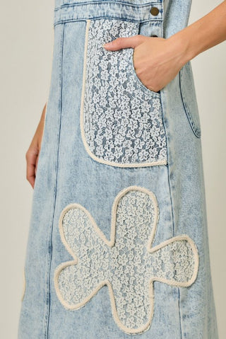 Denim dress with floral patchwork on a plain background