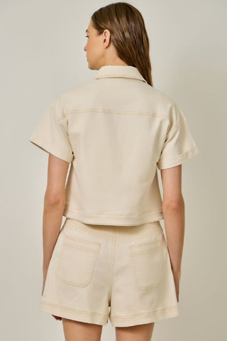 Woman wearing a beige shirt and shorts set on a plain background